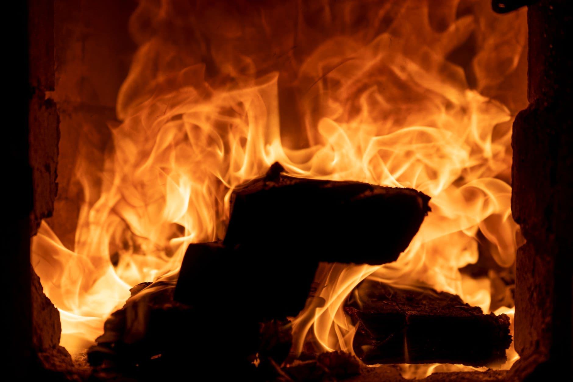 Intensely burning firewood with bright orange flames in a detailed close-up shot.